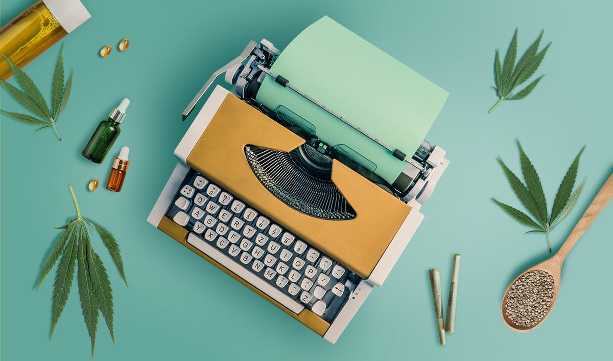 mustard yellow typewriter on teal background with cannabis items on desk