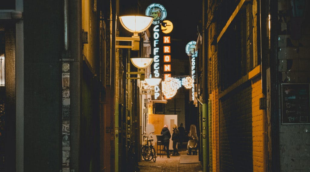 A dark alley at night with bright lights in Amsterdam