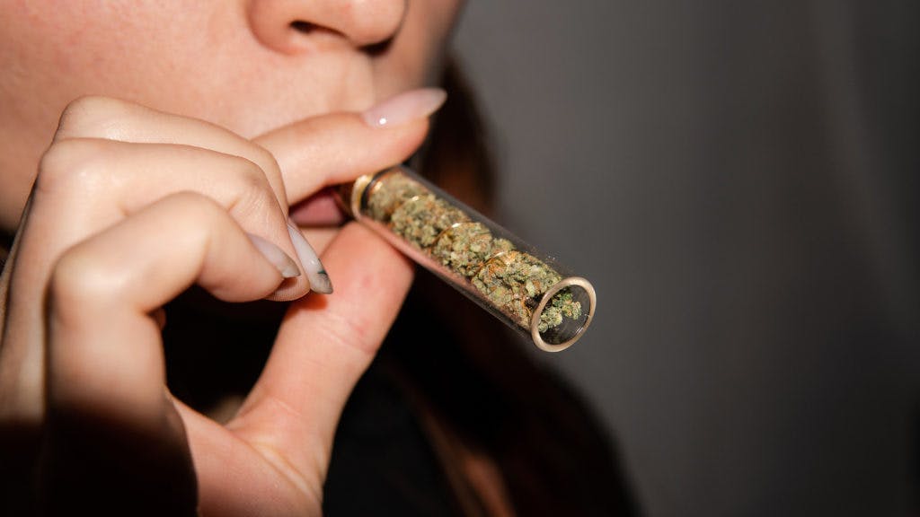 glass joint for smoking marijuana in female hands. Accessories for smoking cannabis in 2020.