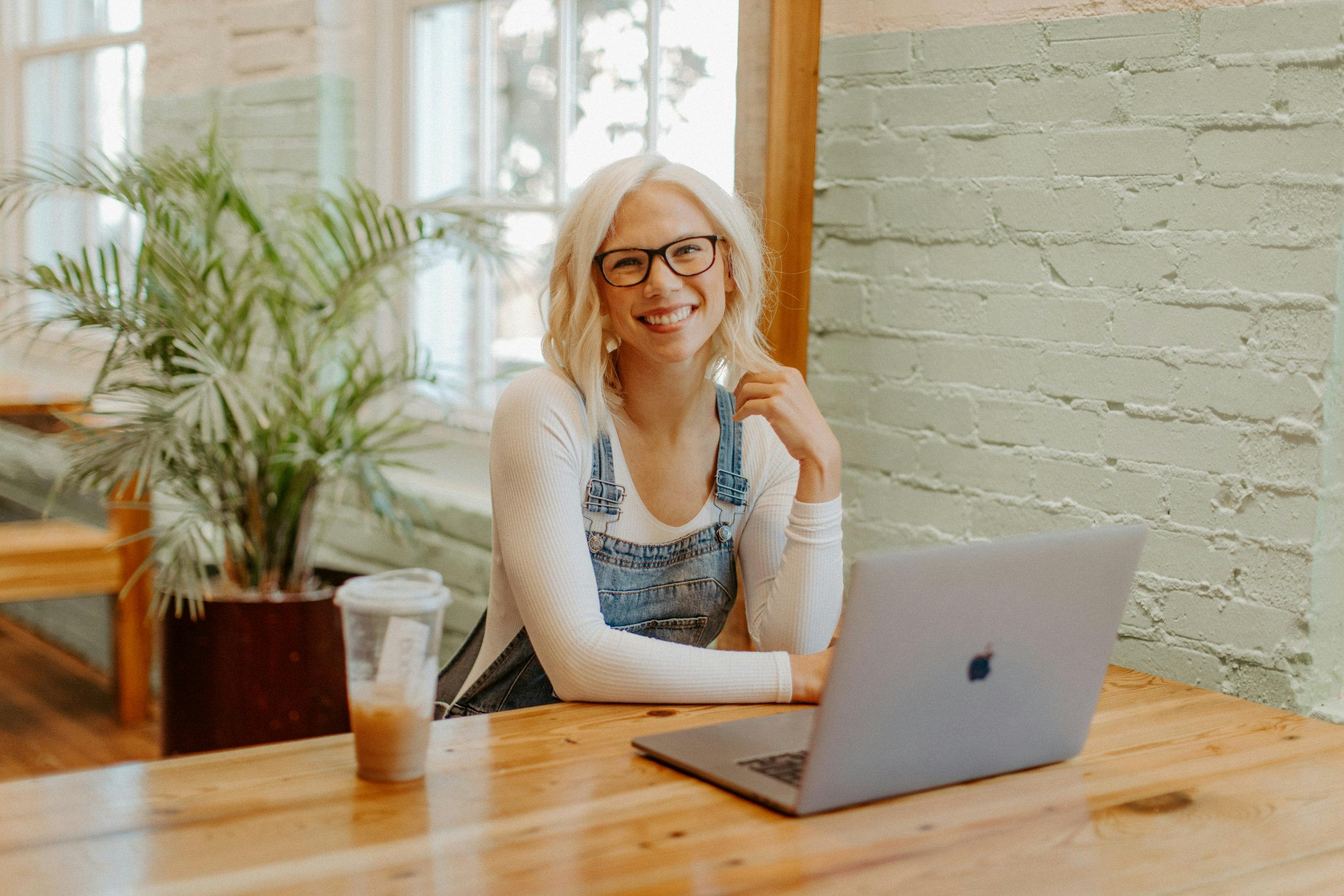 image of Amanda Goetz smiling in front of her desk with a laptop and coffee sitting on it