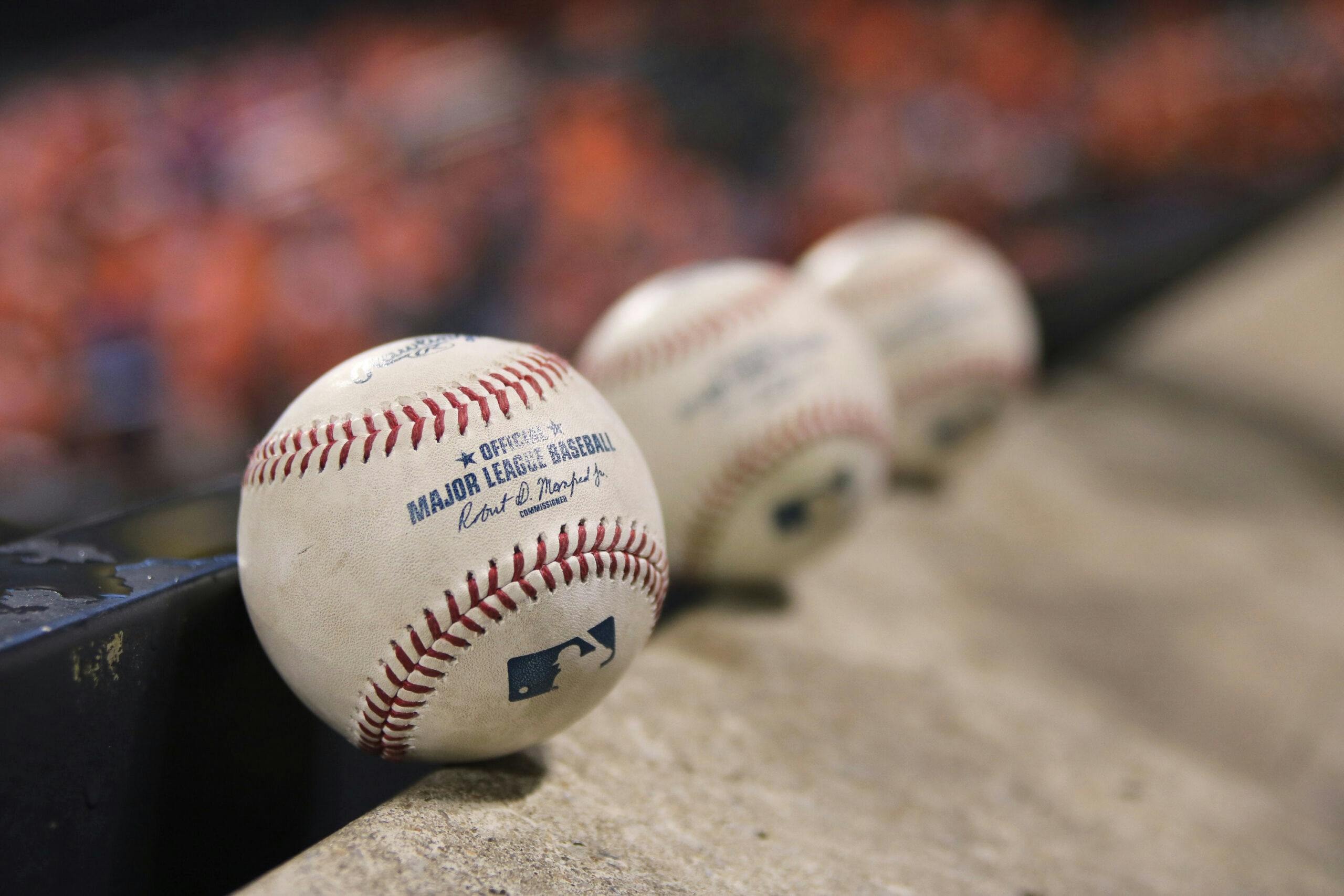 Three official major league baseballs lined up at a baseball game