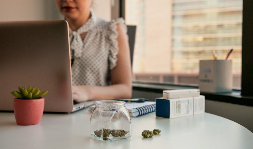 Woman on computer with medical cannabis on desk