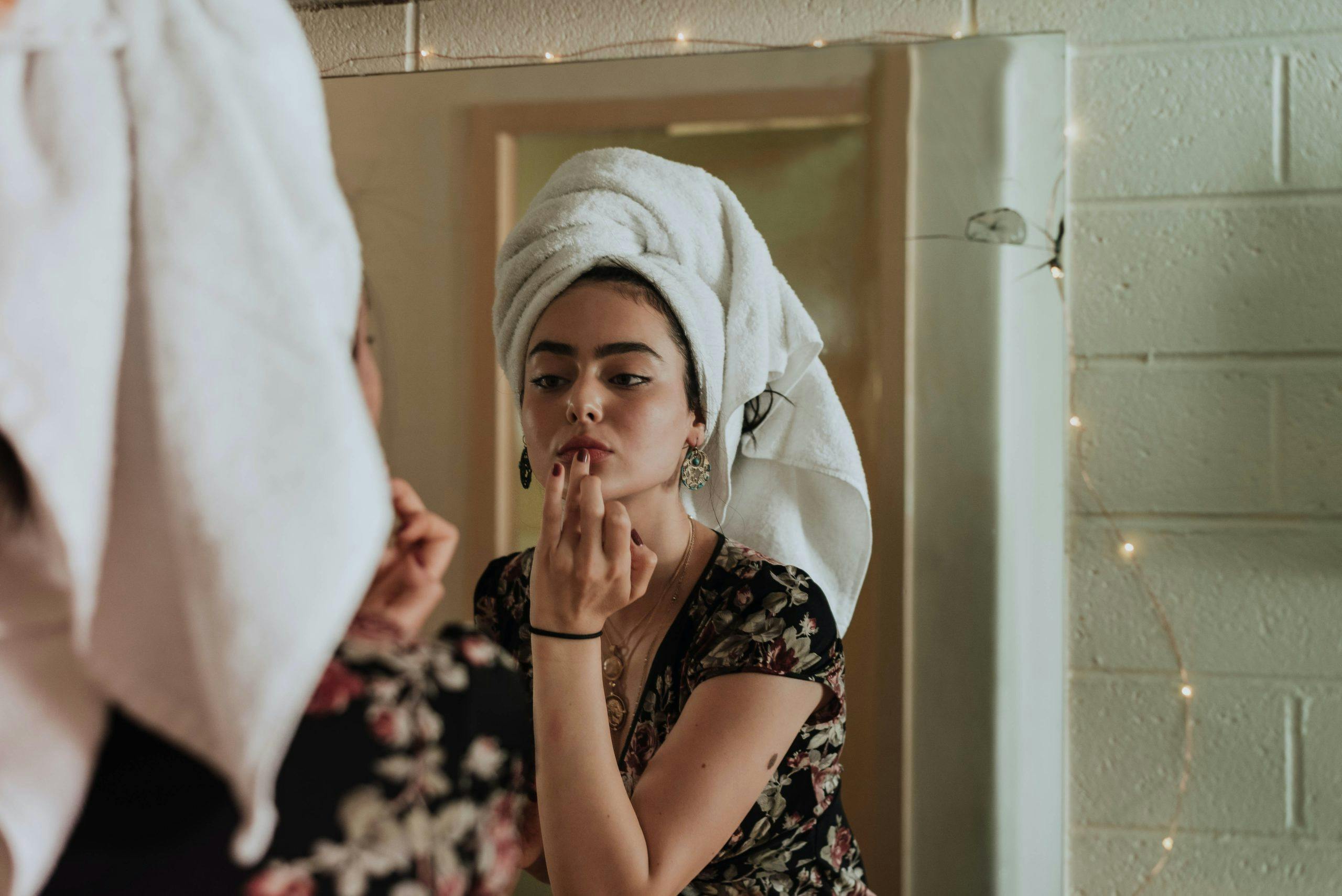 woman applies skincare routine in mirror