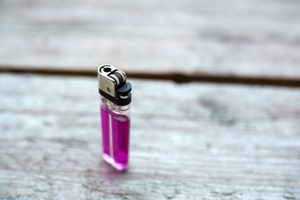 Close up of a pink lighter on a wooden background.