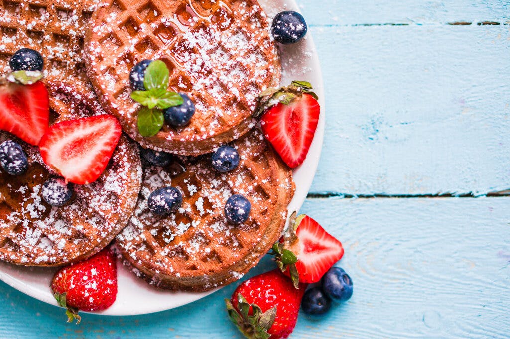 Whole grain waffles with berries on blue wooden background