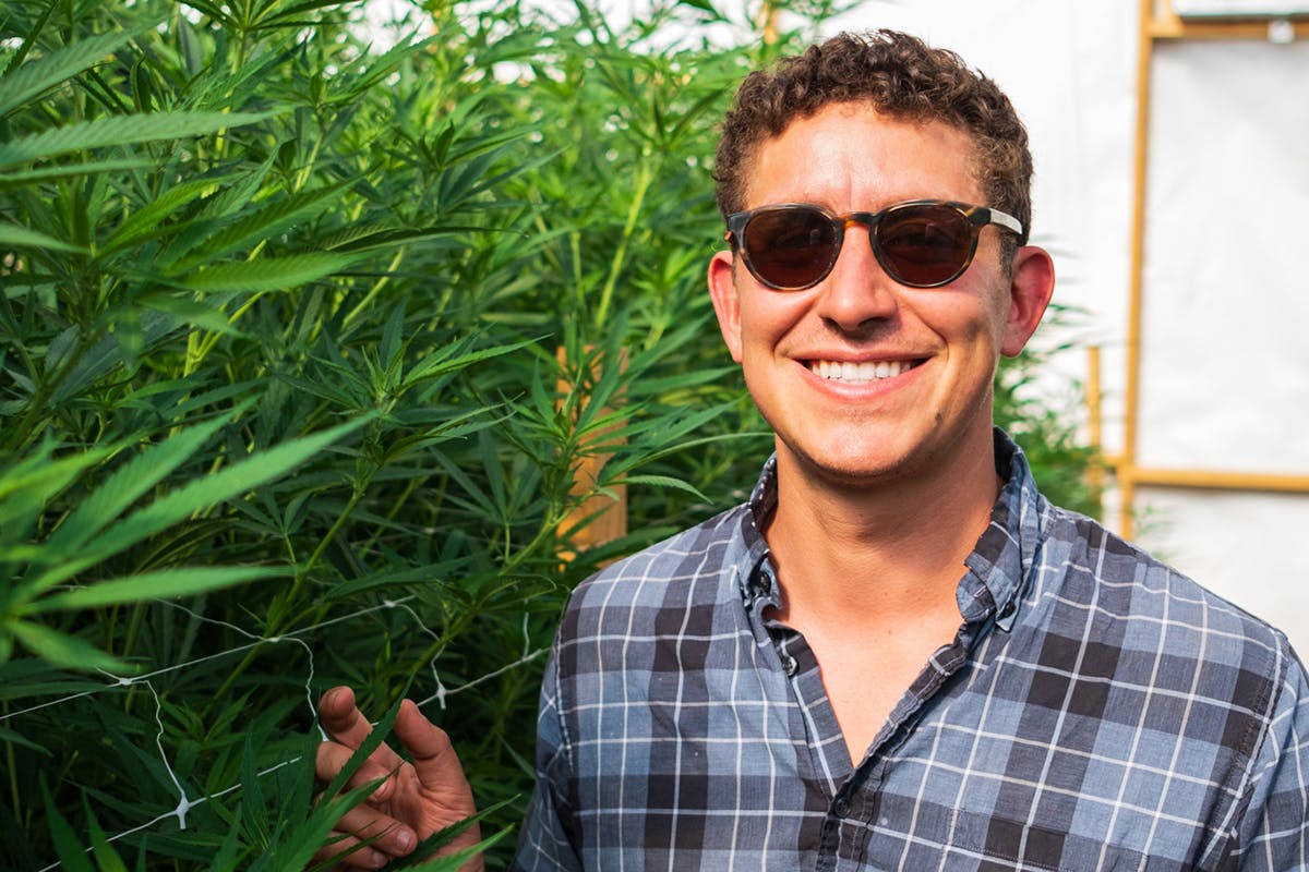 portrait of Lex Corwin next to growing cannabis plants