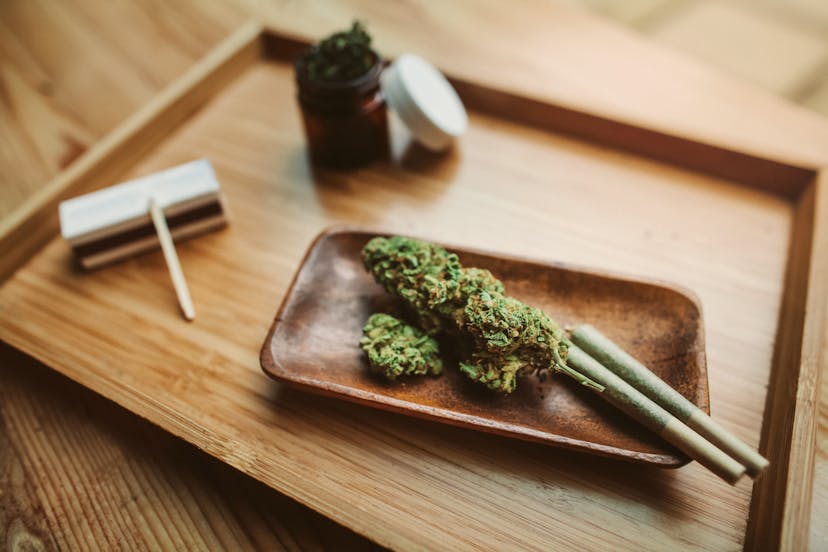 Marijuana joints with cannabis laying on wooden tray at cannabis shop