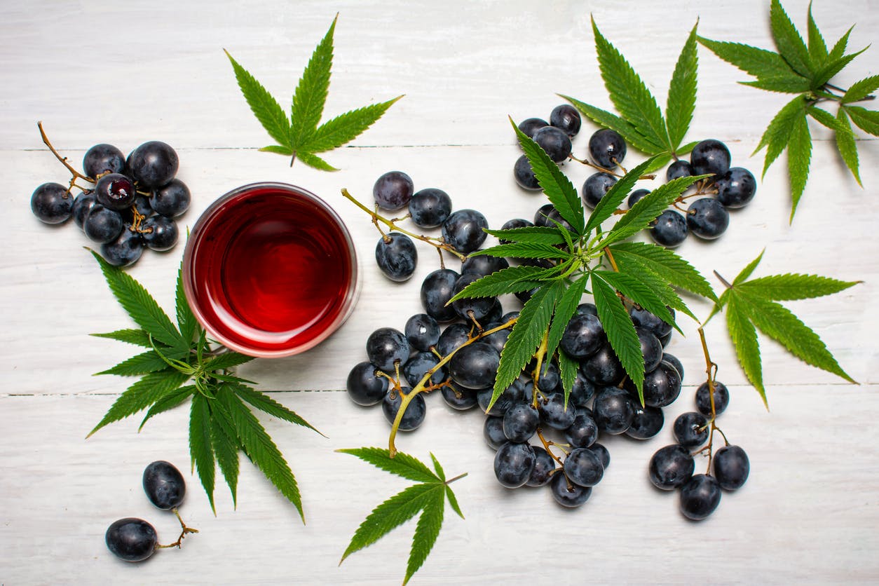 Grape wine and fruits with marijuana leaves on a wooden table top view flat lay