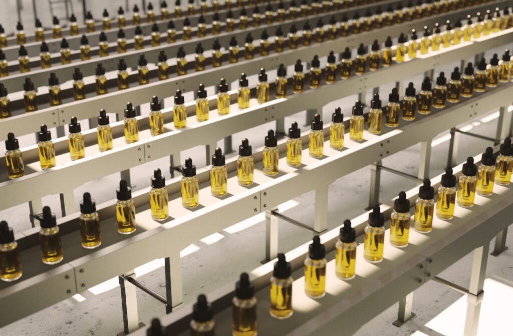 Large amount of CBD oil bottles in rows on production lines inside a pharmaceutical factory.