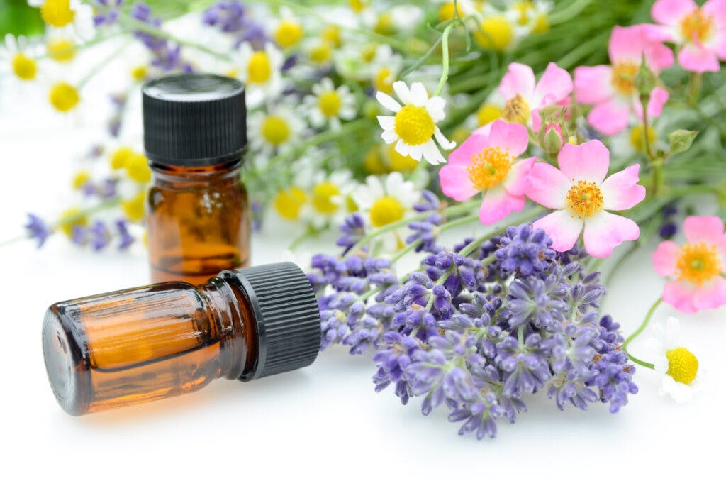essential oils for aromatherapy treatment with herbal flowers using chamomile, roses, and lavender on white background