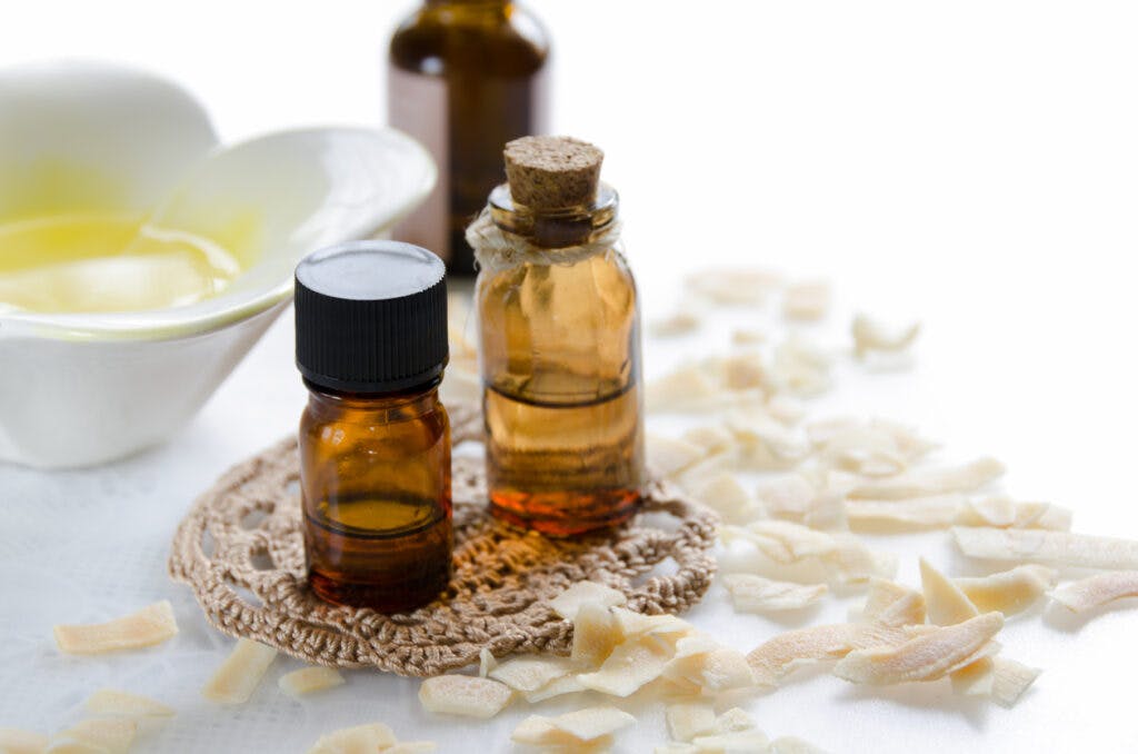 essential oils for aromatherapy treatment with dried coconut flakes on white background