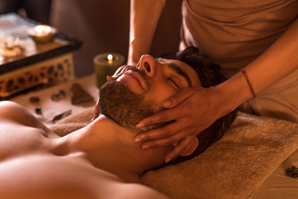 Relaxed man enjoying with eyes closed at the spa during facial massage.