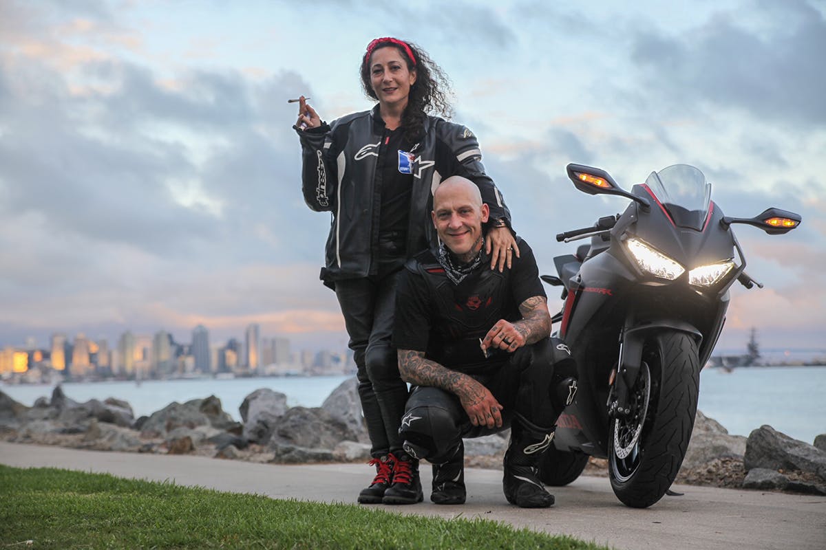 Gina and Steven posing by Steve's motorcycle and smoking joints