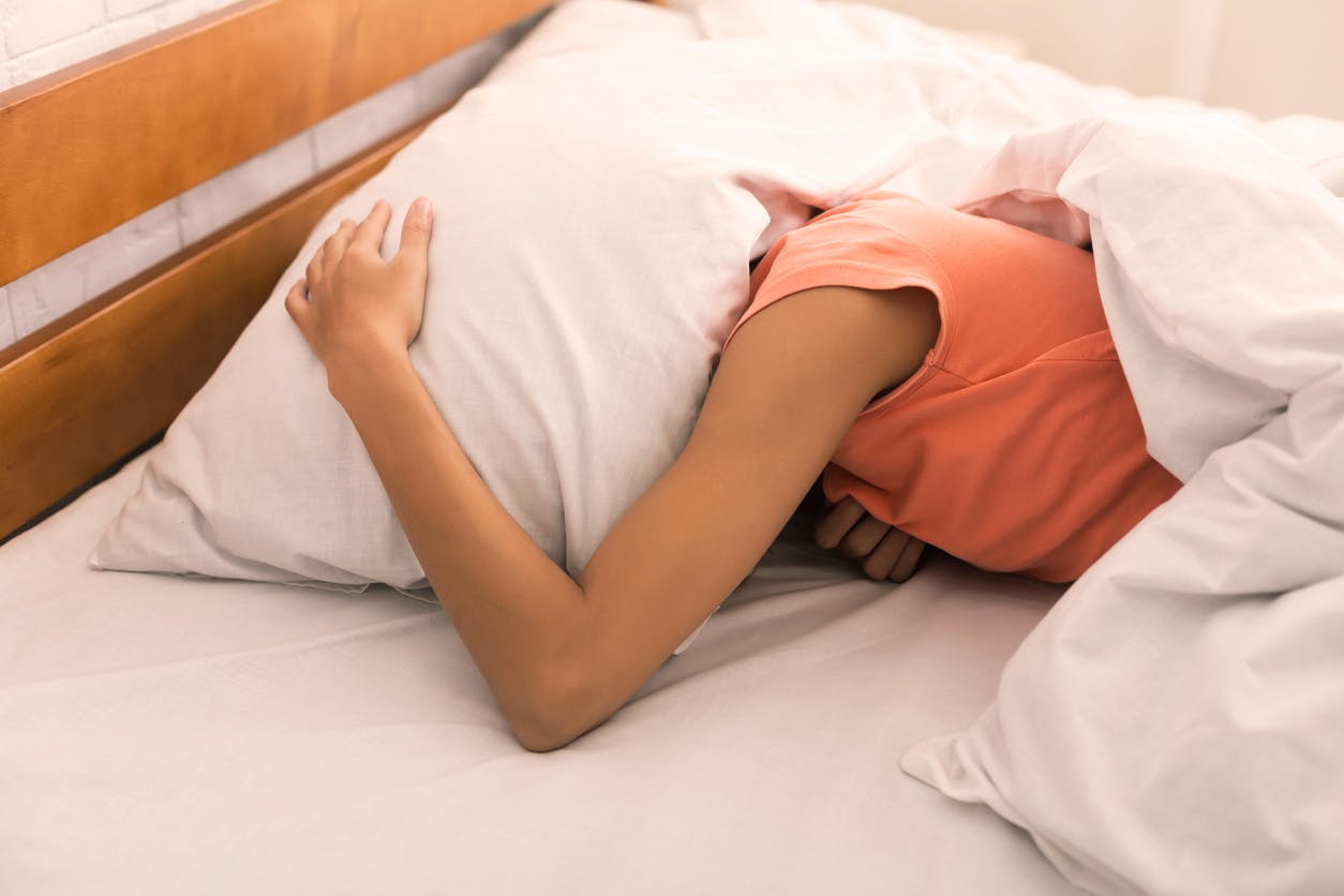 Women covers her head with a pillow in attempt to drown out the sound of ringing in her ears from tinnitus