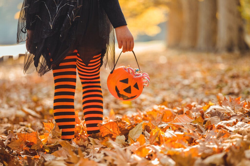 Little girl in witch costume having fun outdoors on Halloween trick or treat