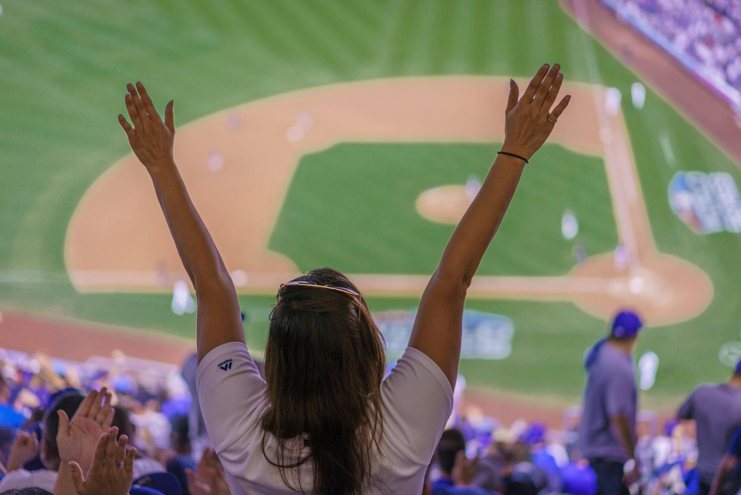 MLB fan jumps up with arms outstretched celebrating