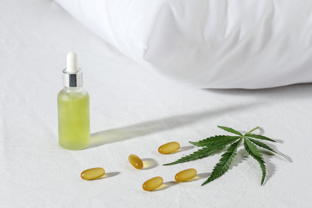 Melotonin production, pills, capsules and cbd oil on the bed. Concept sleep disorder. beat insomnia and restore sleeping routine. Cannabis Branch