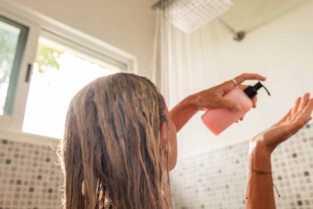 woman uses CBD hair care products as she enjoys the rain shower under the sunlight