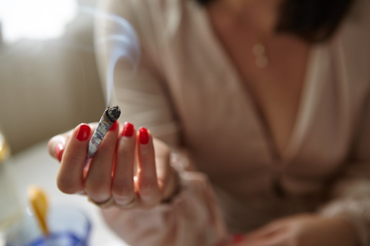 Stylish Woman Smoking a Joint at Home. Hand Model.