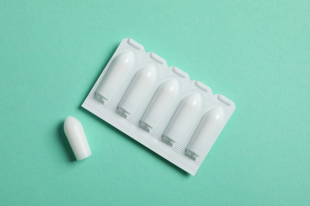 Anal or vaginal candles on mint background, top view