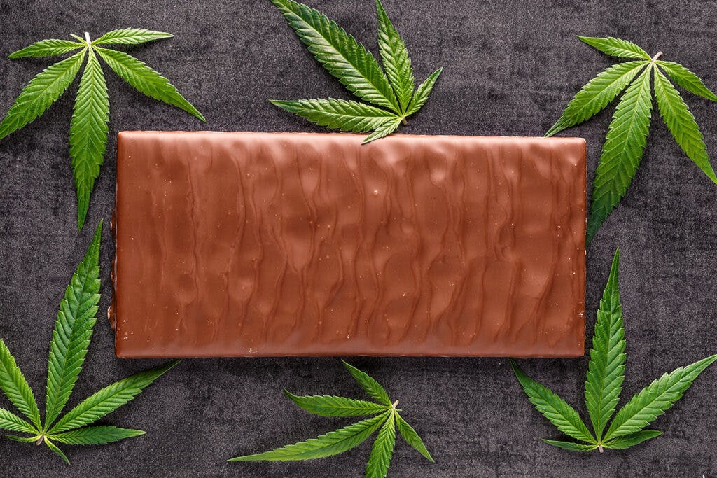 Marijuana leaves on top of chocolate.traditional sponge cake with cannabis weed cbd. Medical marijuana drugs in food dessert, ganja legalization.Stack of chocolate slices with mint leaf on a wooden table.