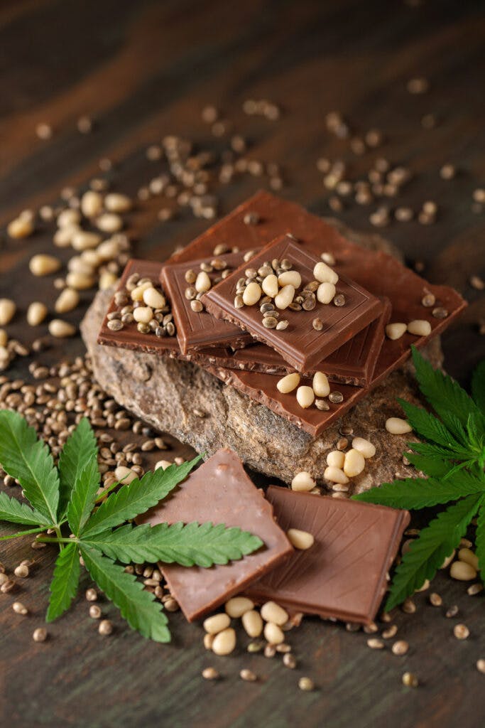 CBD Chocolate with pine nut, cannabis leaves and seeds on wooden background. Healthy take of break