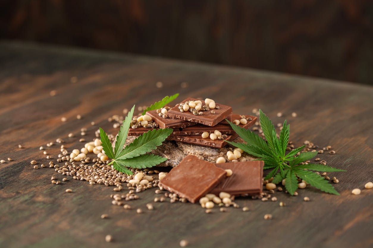 CBD Chocolate recipe with pine nut, cannabis leaves and seeds on wooden background. Healthy take of break