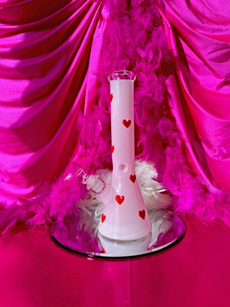 a pink glass bong with red hearts