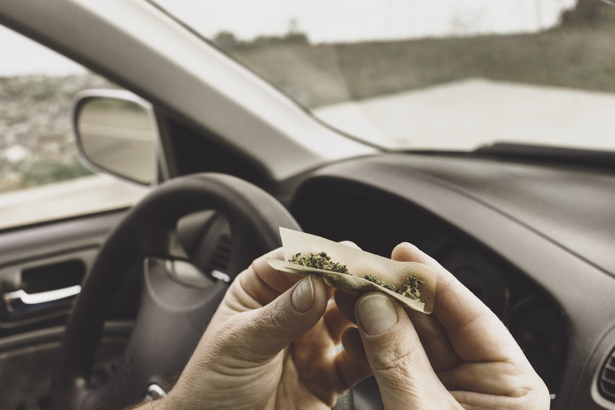 Stock photo of a man smoking marijuana in a vehicle driving a car under the influence of cannabis.