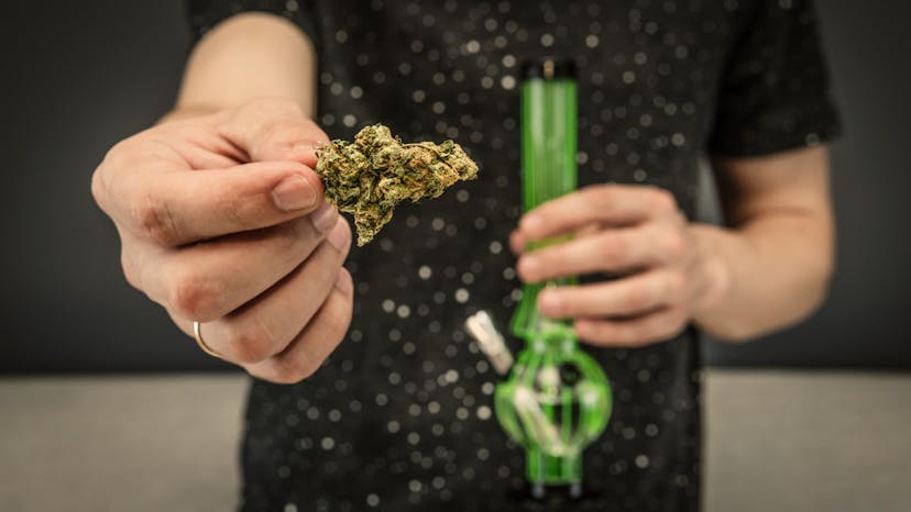 The young person hold in his hand medical marijuana buds and bong. Smoking medical cannabis with bong. Marijuana is a concept of herbal medicine